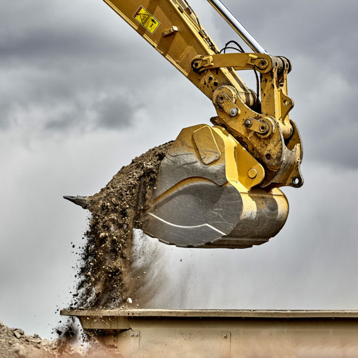 Construction industry heavy equipment excavator moving gravel at jobsite quarry with stormy skies